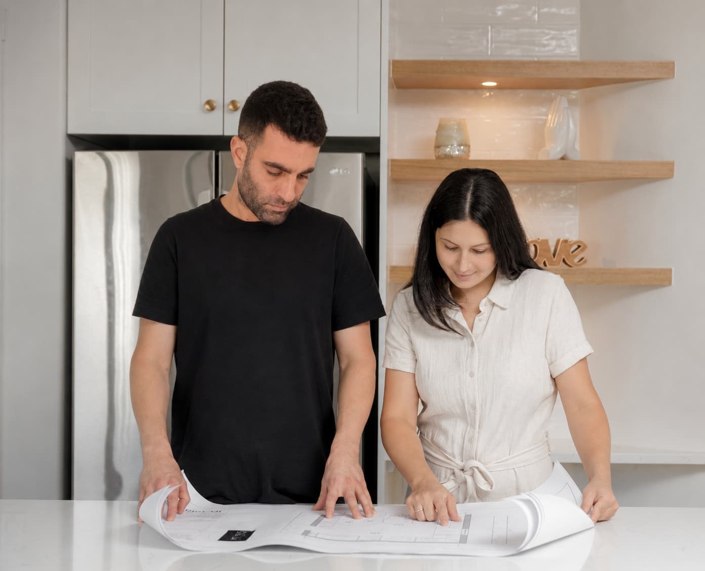 Tom reviewing floor plans with a client at a kitchen island